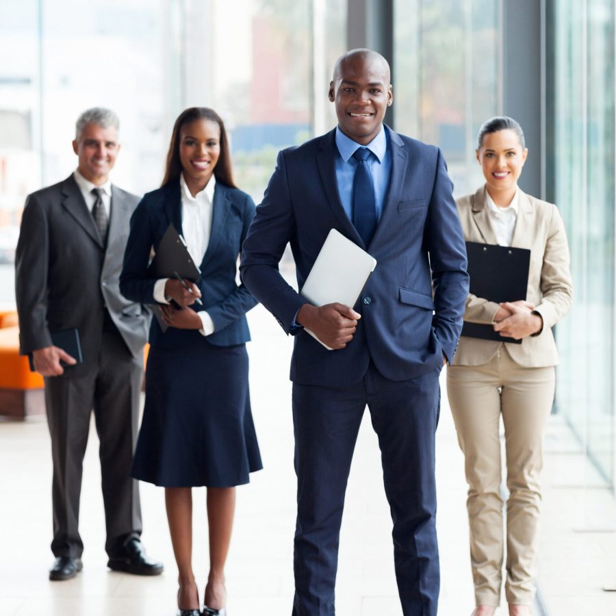 confident male African business leader and team in office