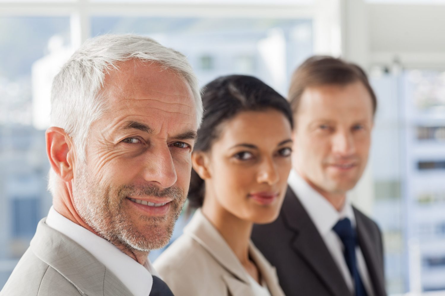 Smiling business people looking in the same way in their office